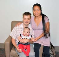 Baby Megha and her parents sitting on a chair