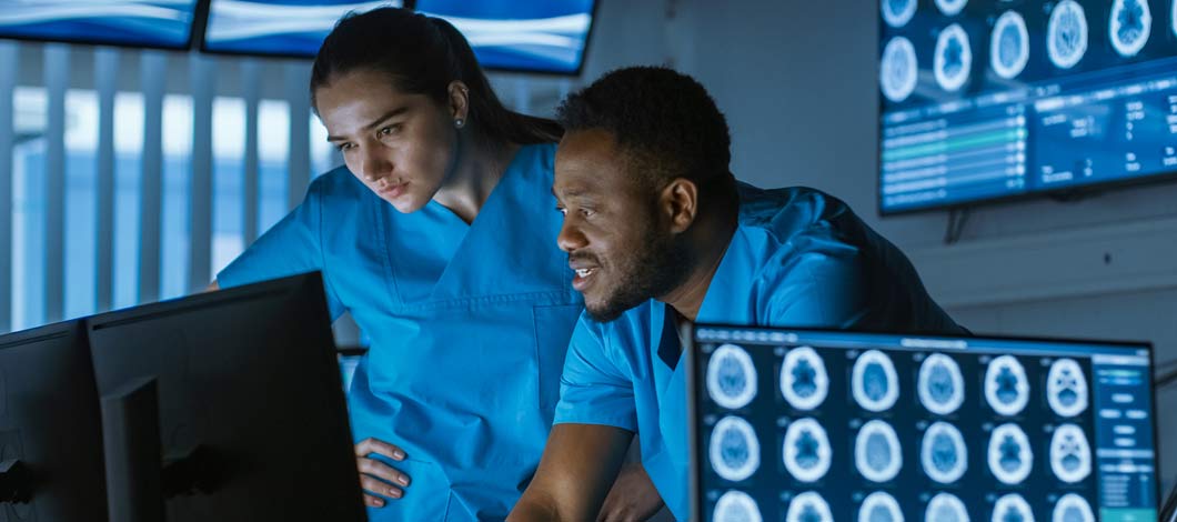 Clinician scientists looking at computer with scans displayed