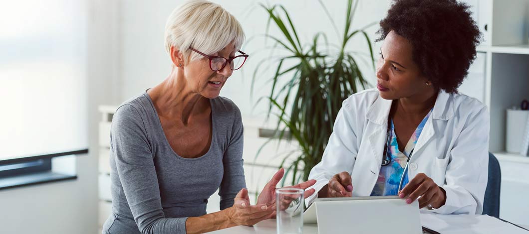 Older Caucasian woman patient meeting with Black female physician