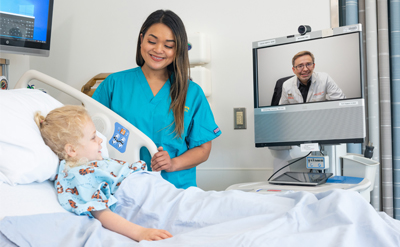 Nurse and child looking at computer screen with doctor on it. (c) UC Davis Regents. Rights reserved.