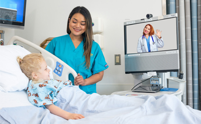 Nurse and child looking at computer screen with doctor on it. (c) UC Davis Regents. Rights reserved.