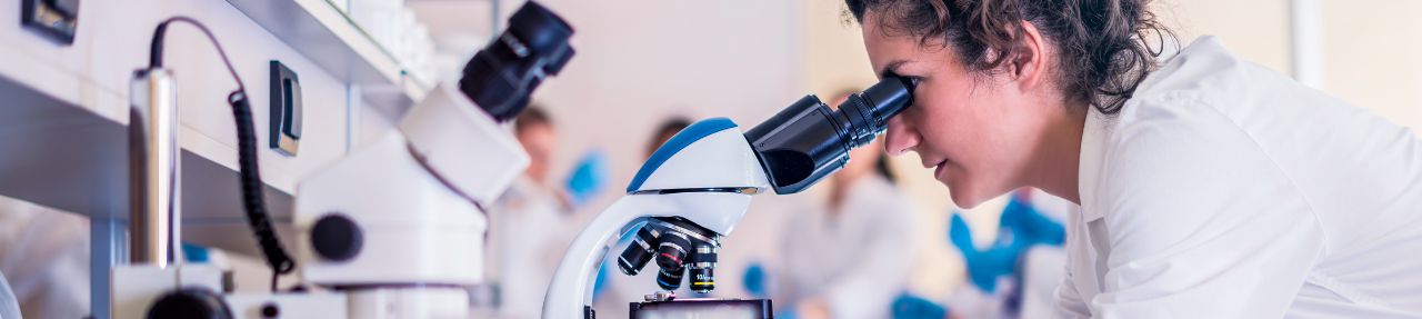Researcher looks through a microscope (c) UC Regents. All rights reserved.