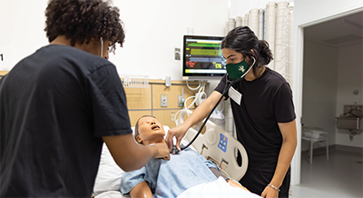 Levert Bryant, left, and a fellow SHINES participant get hands-on experience in a hospital manikin simulation.