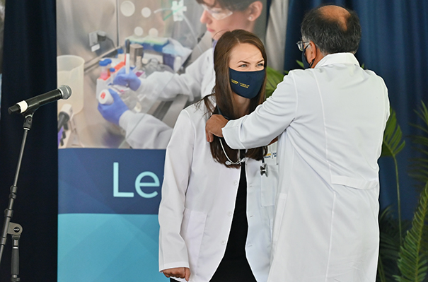 Shania Westmoreland receives her stethoscope from Associate Dean for Students Sharad Jain