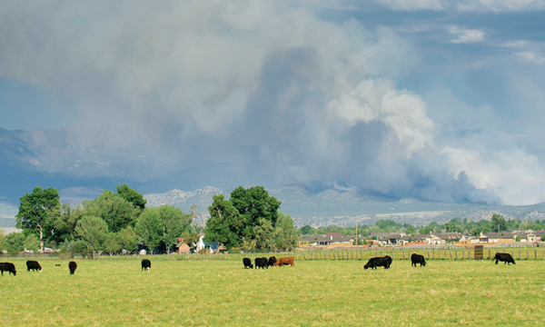 rural home with wildfire smoke in the distance behind