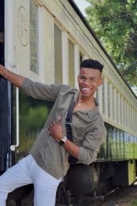 Man smiling leaning on the side of a train.