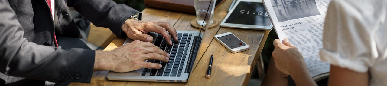 Man typing on laptop keyboard next to woman with newspaper. (C) Pixabay. All rights reserved. 