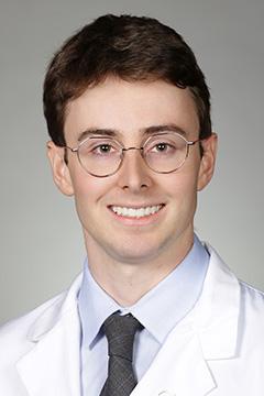 medical student in white coat smiling