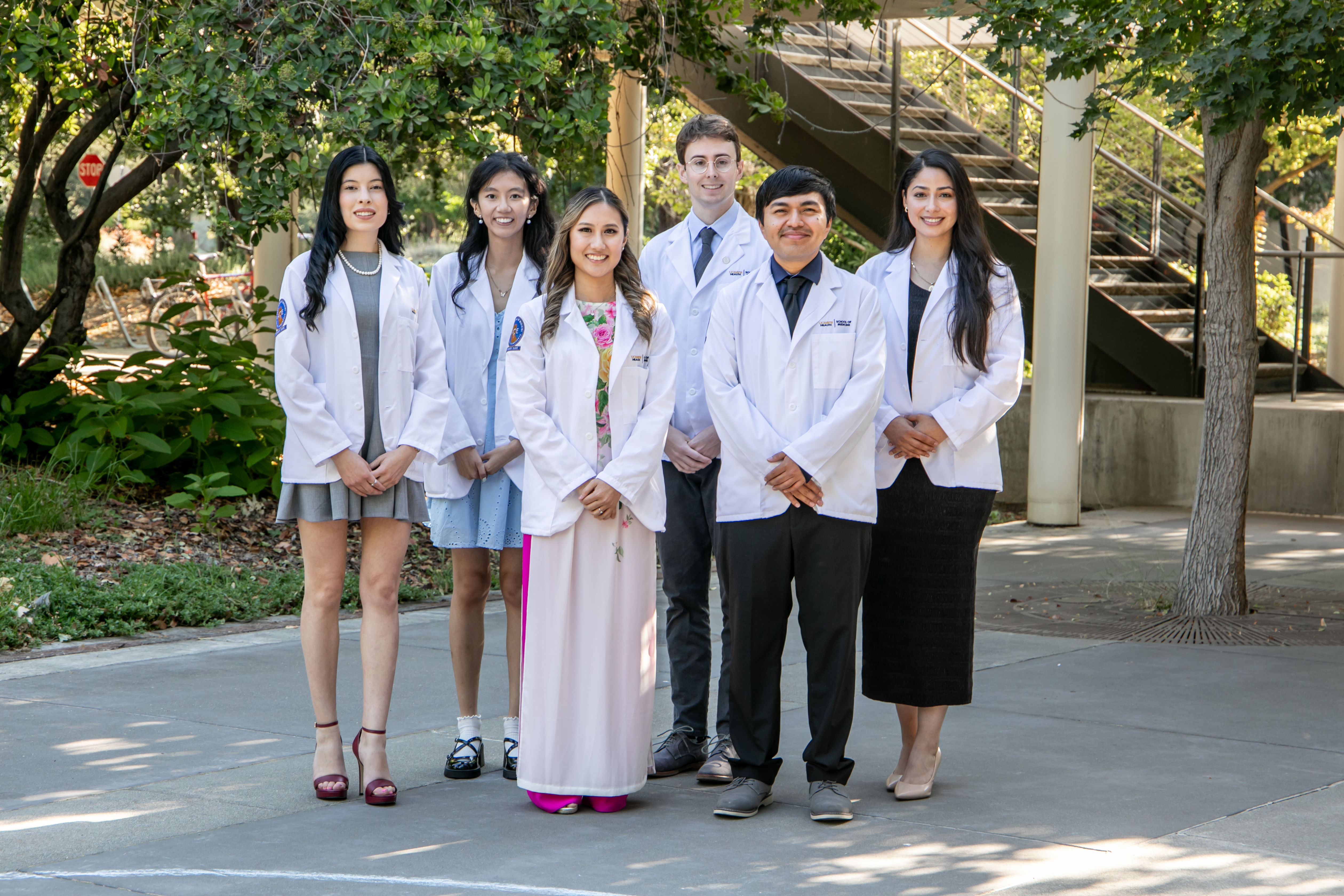 the 2025 cohort of accelerated medical students posed in white coats in outdoor setting