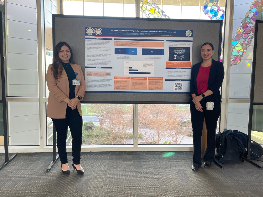 Four people standing in front of a research poster at a conference 