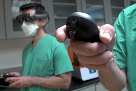 Clinicians holding controlers, viewing synthesized medical imaging data as a hologram in physical space.
