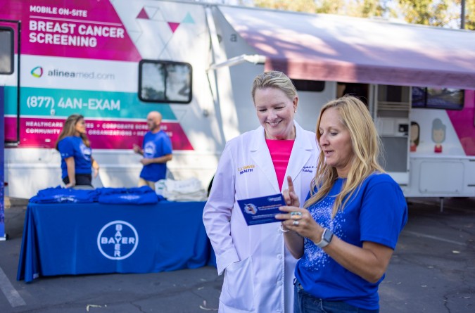 A physician and a nurse meet outside of the UC Davis Health Mobile Mamovan at a community screening event