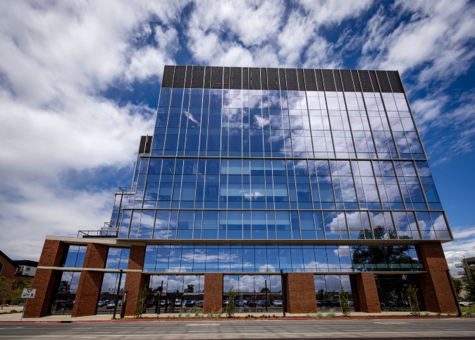 A photo of an Aggie Square building with the sky and clouds reflected in the windows.