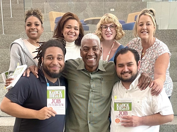 A group of people and two are holding books. 