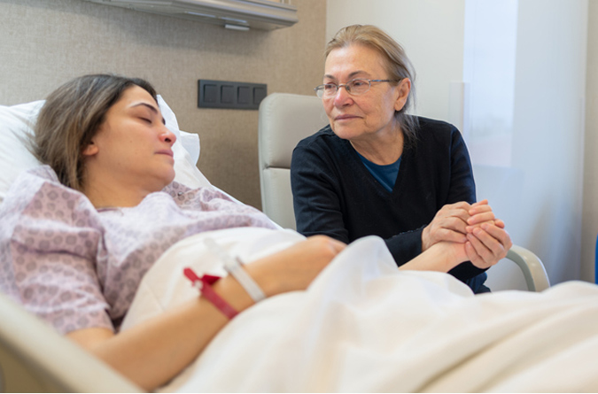 An elderly woman comforting a hospital patient.