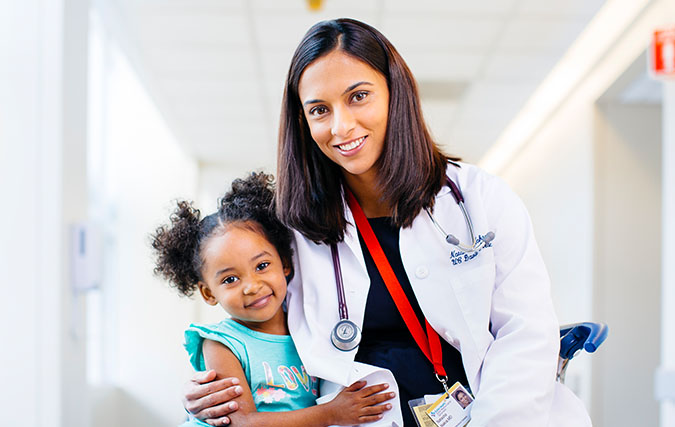 Photo of Natasha Nakra, M.D. with her arm around a child.