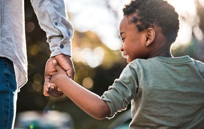 Smiling boy holding hand of man while they walk