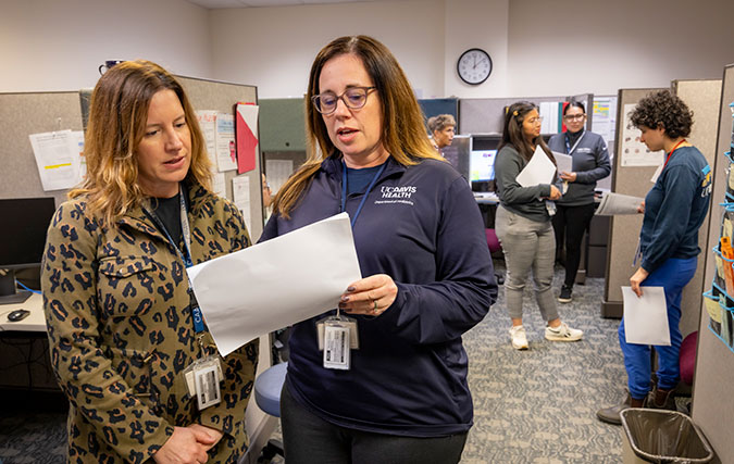 Circle Clinic staff working in office, 2 look over form and 4 work in background