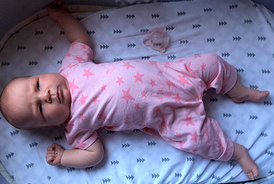 Infant Aria in pink pajamas in a crib