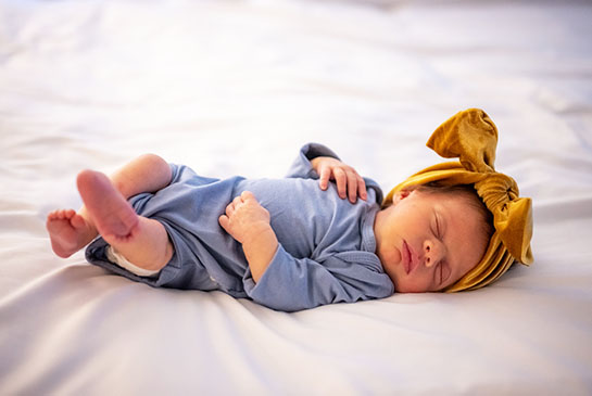 Baby Robbie lying on a bed with cute head bow