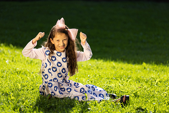 Grace sitting in the grass flexing her muscles