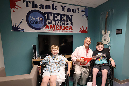 2 young boys in wheelchairs inside the Caner Teen Center with physician.