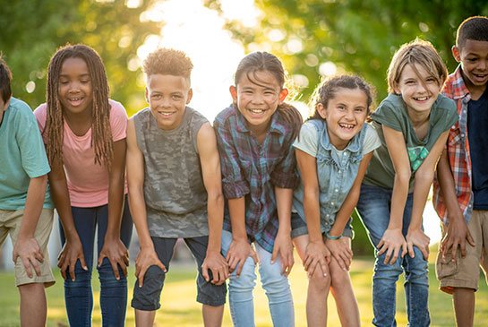 6 teens standing shoulder to shoulder with sun in background.
