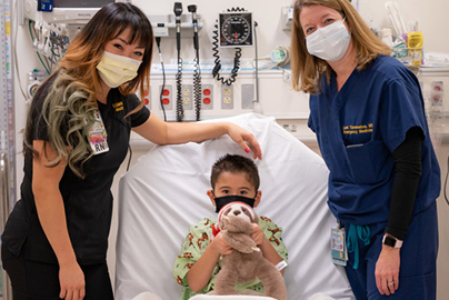 Two nurses standing bedside with a young patient.