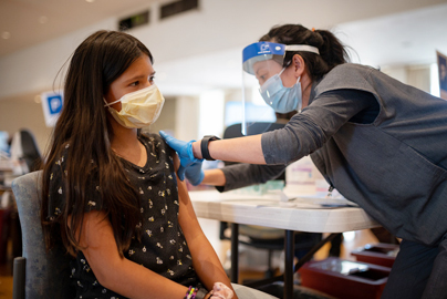 Teen girl receiving a vaccination from a healthcare worker.