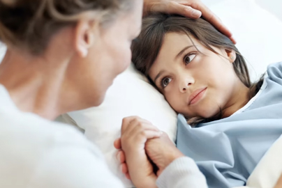 A young child in a hospital bed looking at an adult.