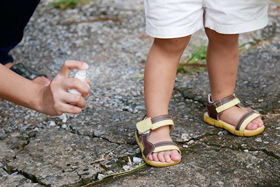 Child being sprayed with mosquito repellent.