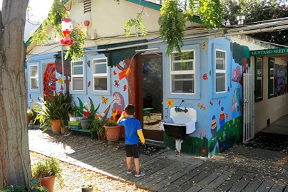 A child standing outside of a Mustard School building.