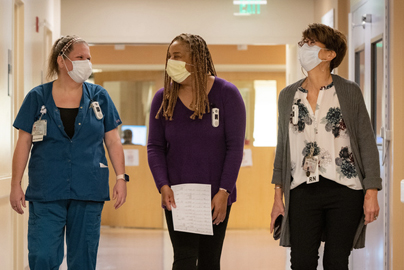 Three medical workers walking down the hallway of a hospital.