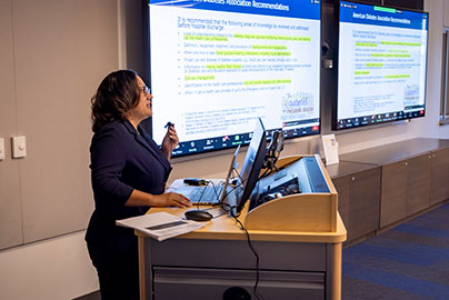 Circle Clinic Values, Evidence Based, Physician talks at podium while presenting slides of evidence.