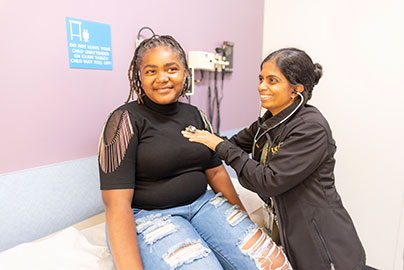 Adolescent woman with physician in exam room