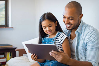 Dad with daughter holding tablet, at home