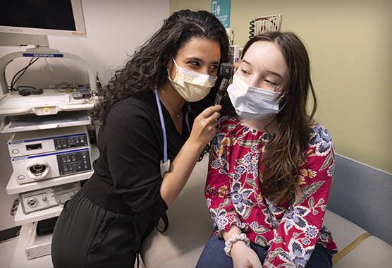 Pulmonologist Abu Nasser performing check-up on young patient in clinic office