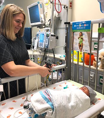 UC Davis neonatologist Kristin Hoffman secures a webcam onto a NICU bed. 