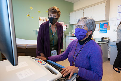 Katy Carlsen and Albina Gogo work on computer in clinic office.