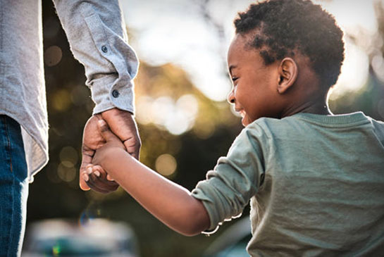 Young happy boy holding a man's hand and walking