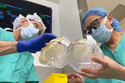 surgeons looking at a 3D model of the twin's skulls.