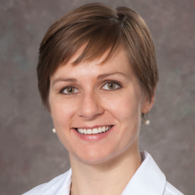 Elizabeth Magnan wears a white medical coat and smiles.