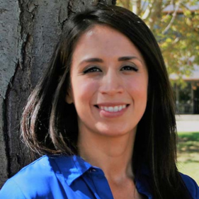 Cindy Valencia, of the Center for Healthcare Policy and Research, smiles next to a tree.