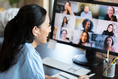Person participating in a video call on a computer with multiple participants displayed on screen
