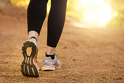 A woman's legs walking outside toward the horizon.