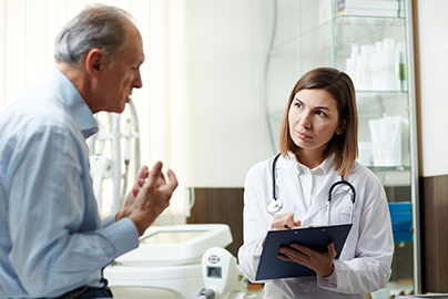 Patient talking to doctor holding a clipboard. 