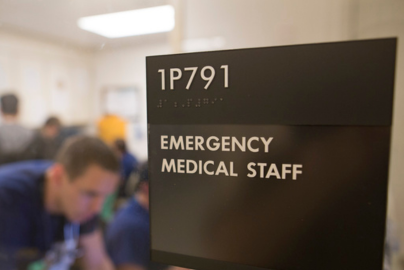 An emergency medical staff sign next to a door.