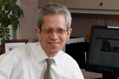 Photo of Patrick Romano sitting at a desk and smiling.