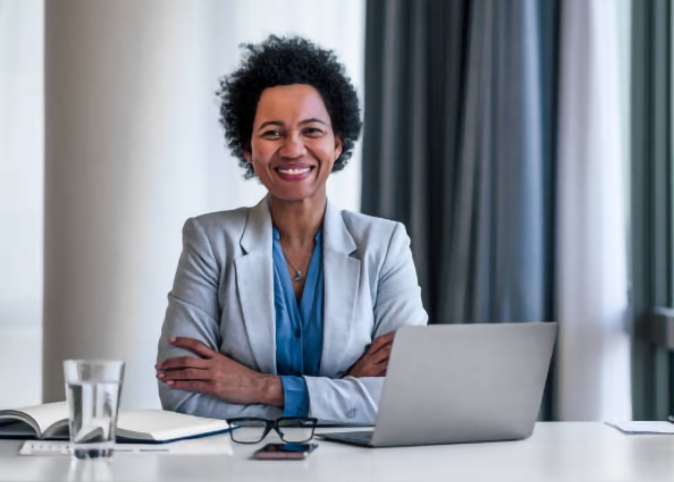 woman in suit sitting at desk smiling