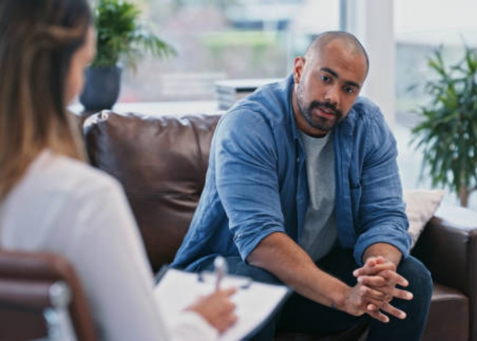 man sitting on couch talking to therapist